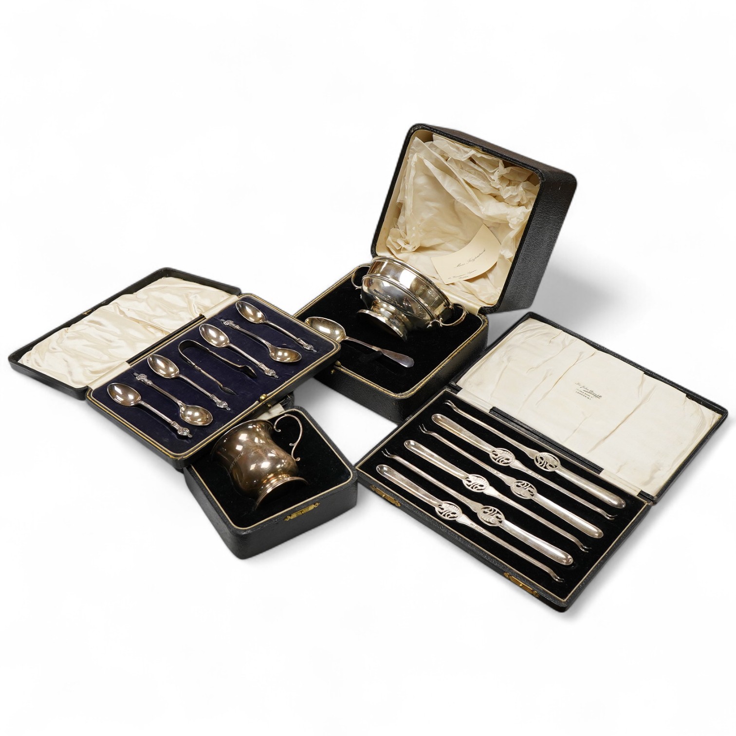 Four assorted cased silver sets including two handled christening bowl and spoon, Birmingham, 1934, a similar christening mug, set of six teaspoons with sugar tongs and six George V lobster picks.